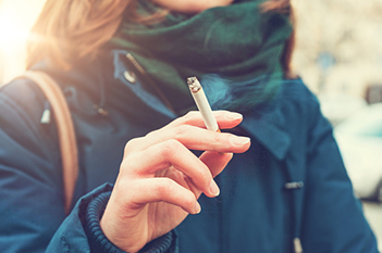Woman holding a cigarette learns risks of smoking to oral health